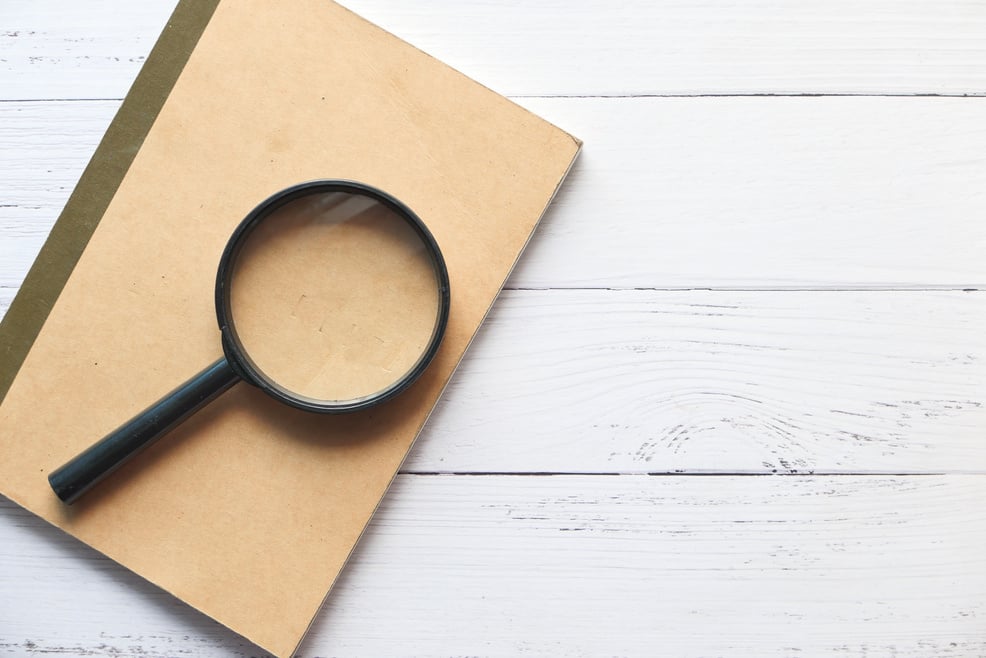 Open Book and Magnifying Glass on Table.